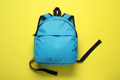 Photo of Stylish light blue backpack on yellow background, top view