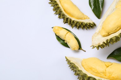 Photo of Pieces of fresh ripe durian and leaves on white background, flat lay. Space for text