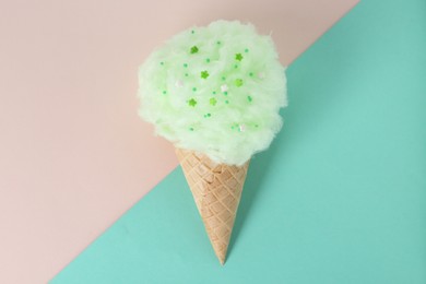 Photo of Sweet cotton candy in waffle cone on color background, top view