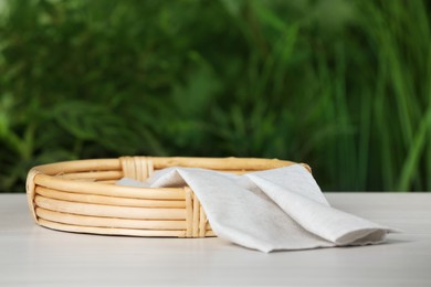 Stylish wicker tray with cloth on white table against blurred background