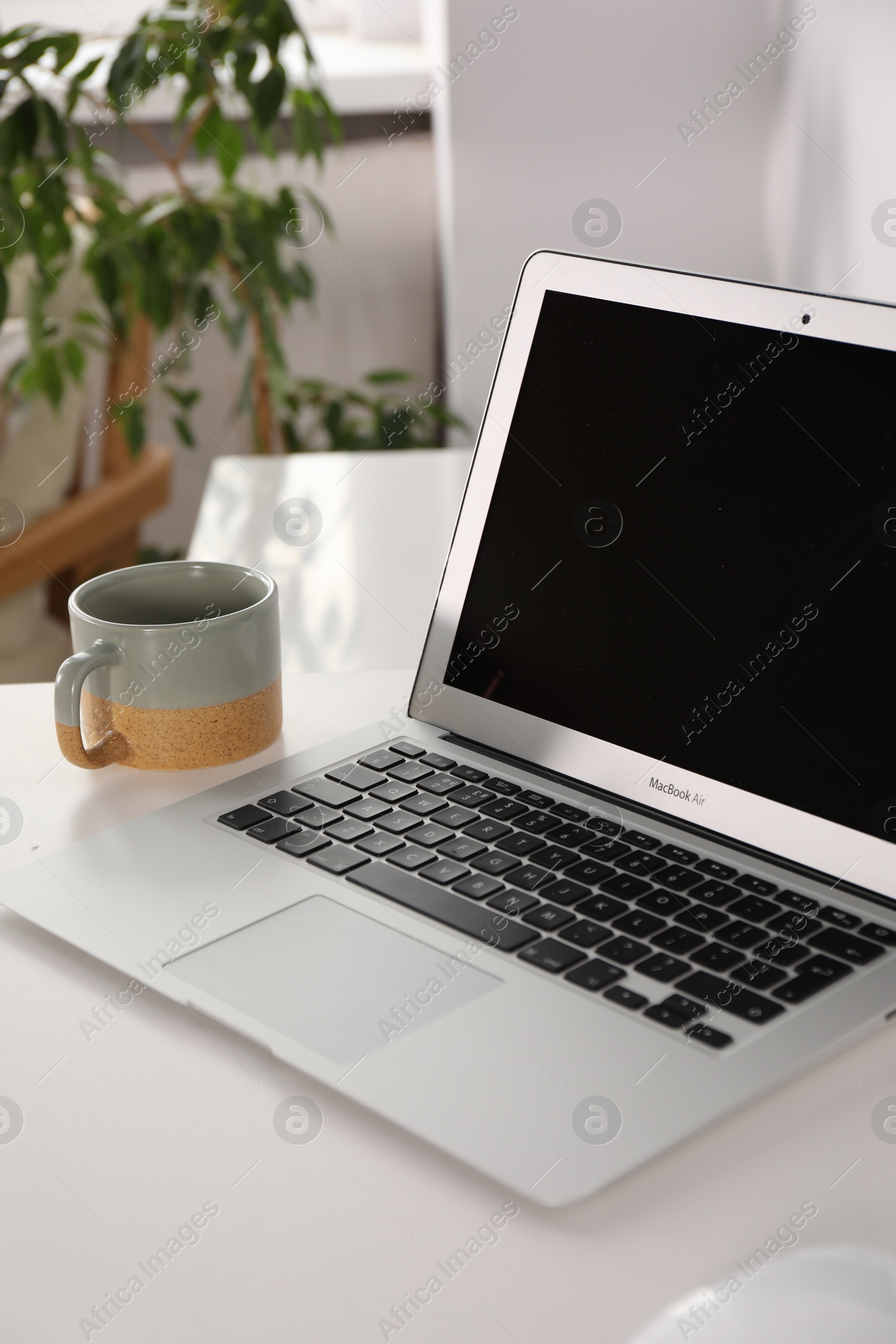 Photo of Beautiful workplace with laptop on white wooden table in room