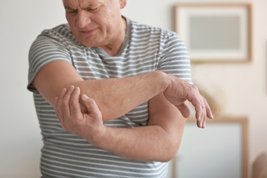 Photo of Mature man suffering from elbow pain at home