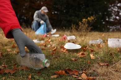 People collecting garbage in nature, closeup of hand with bottle