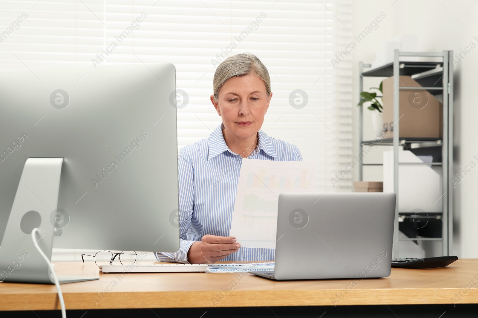 Photo of Senior accountant working at wooden desk in office