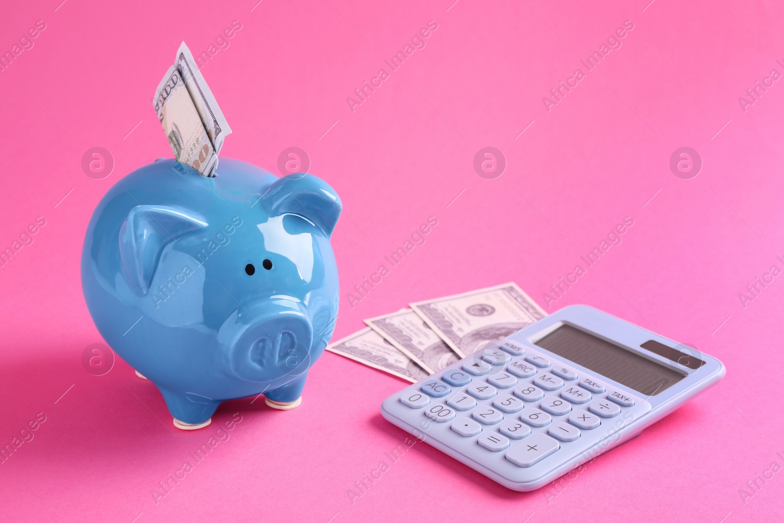 Photo of Financial savings. Piggy bank, dollar banknotes and calculator on pink background