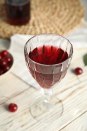 Photo of Delicious cherry wine with ripe juicy berries on white wooden table