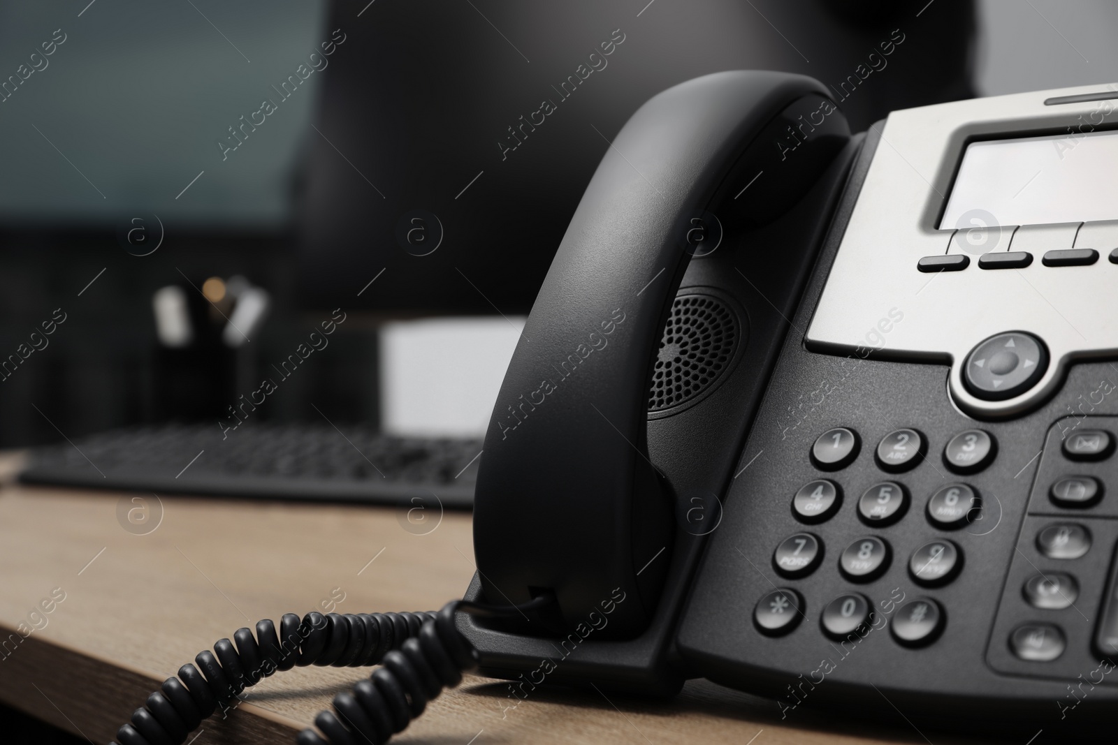 Photo of Stationary phone on wooden desk in office, closeup. Hotline service