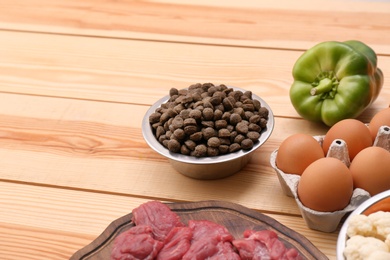 Composition with dry and natural dog food on wooden background