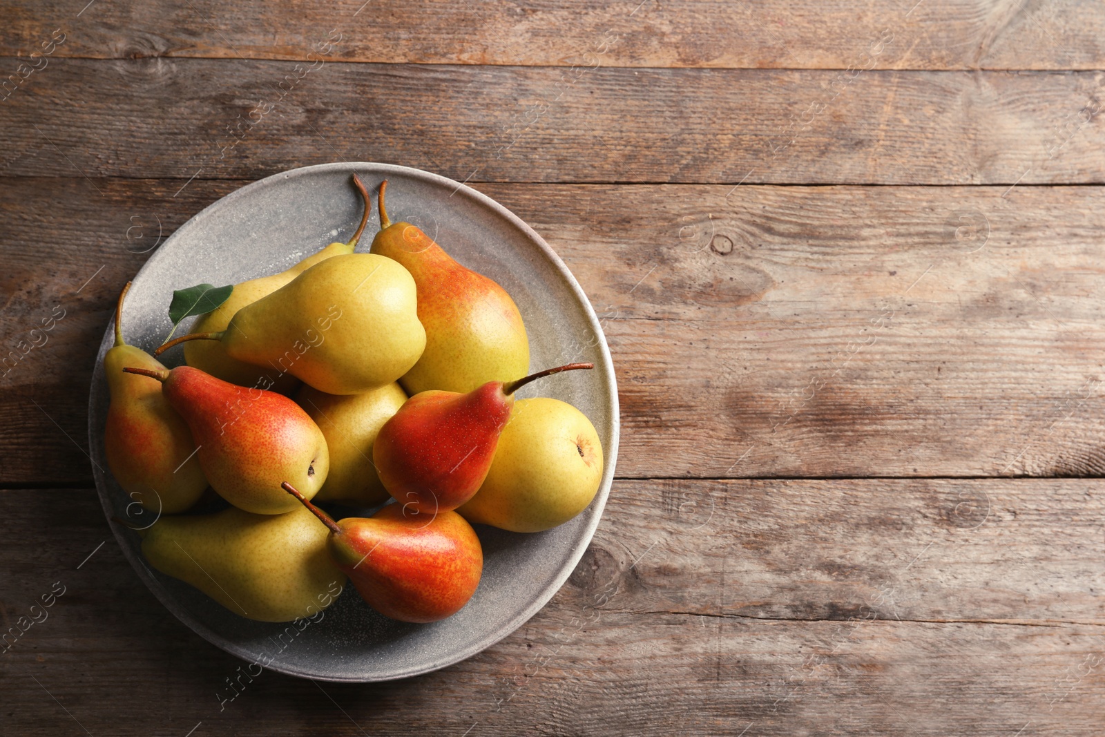 Photo of Plate with ripe pears on wooden background, top view. Space for text