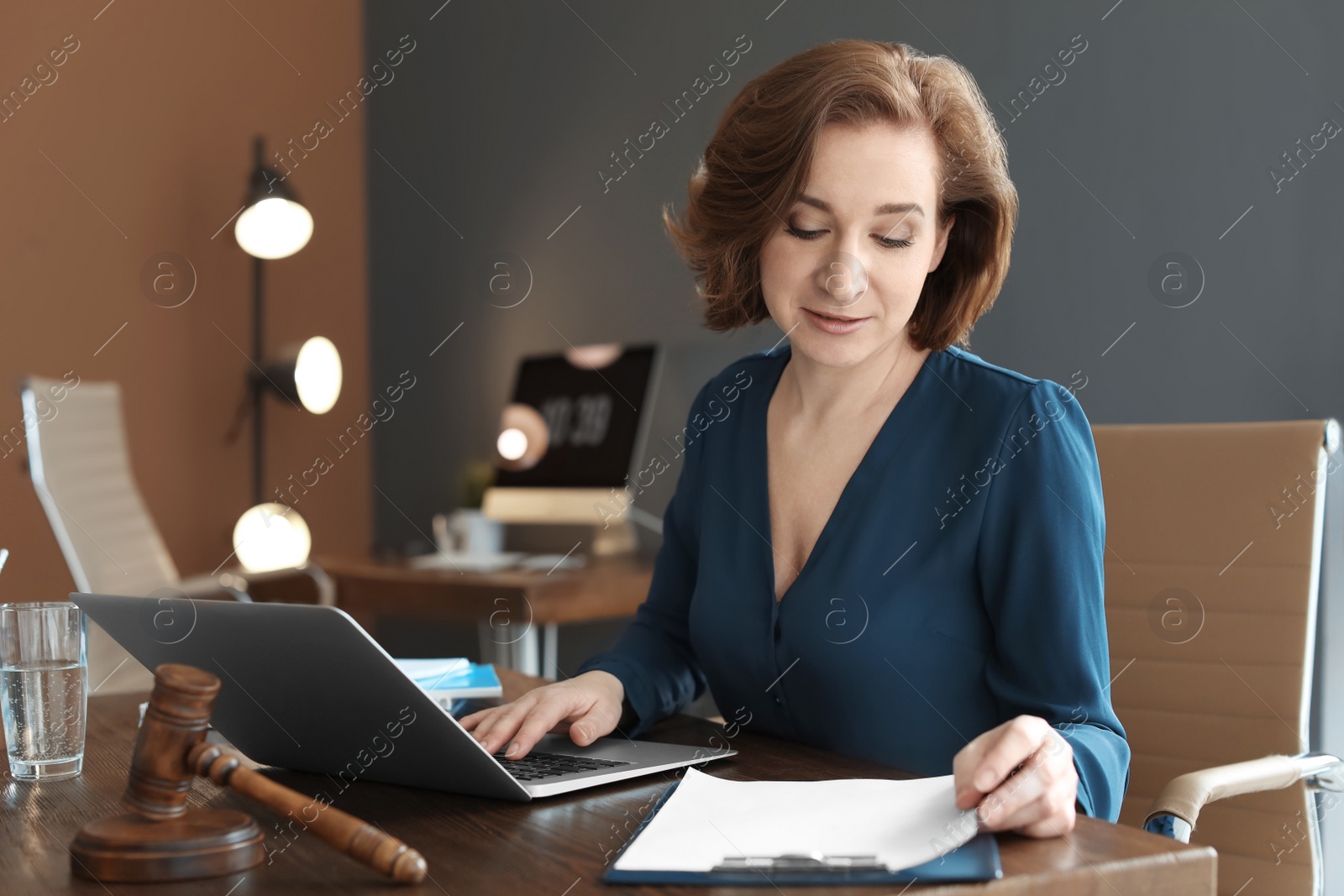 Photo of Female lawyer working with laptop at table in office