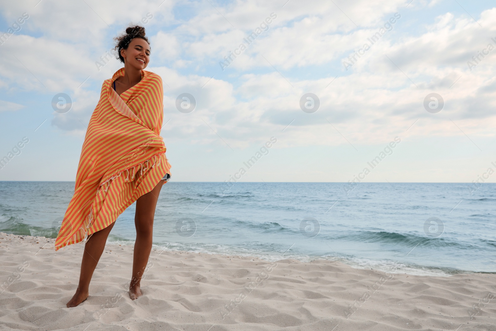 Photo of Beautiful African American woman with beach towel on seashore