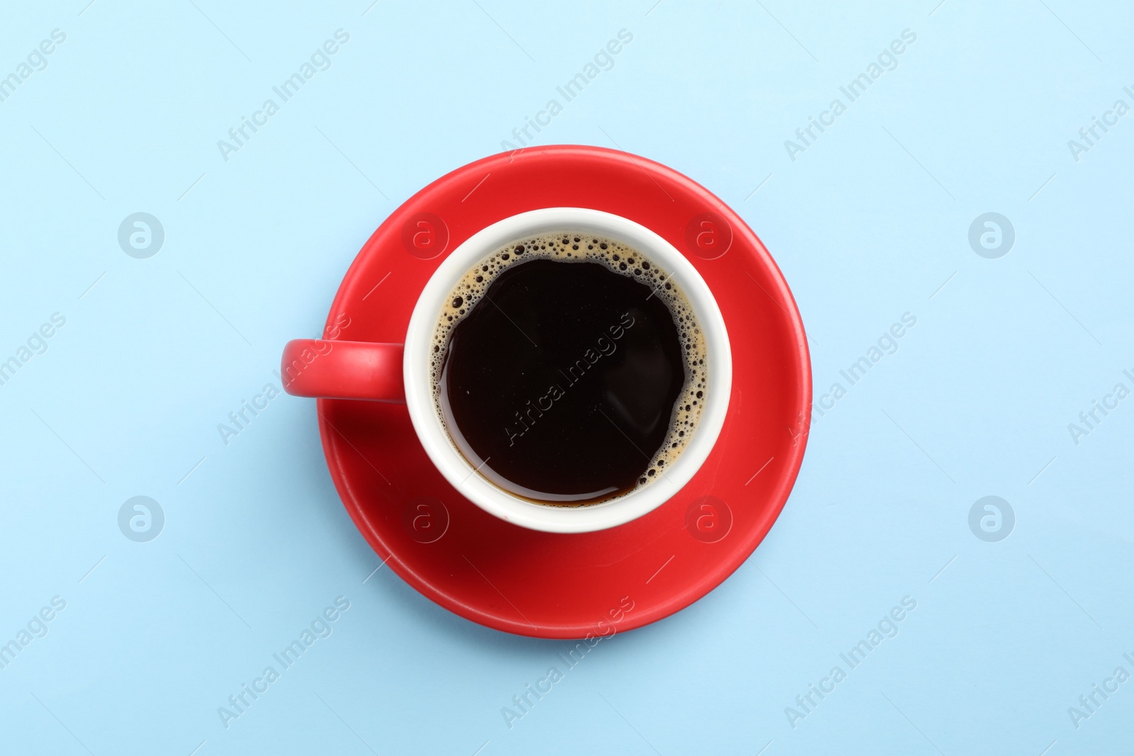 Photo of Aromatic coffee in cup on light blue background, top view