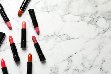 Different lipsticks and space for text on marble background, flat lay