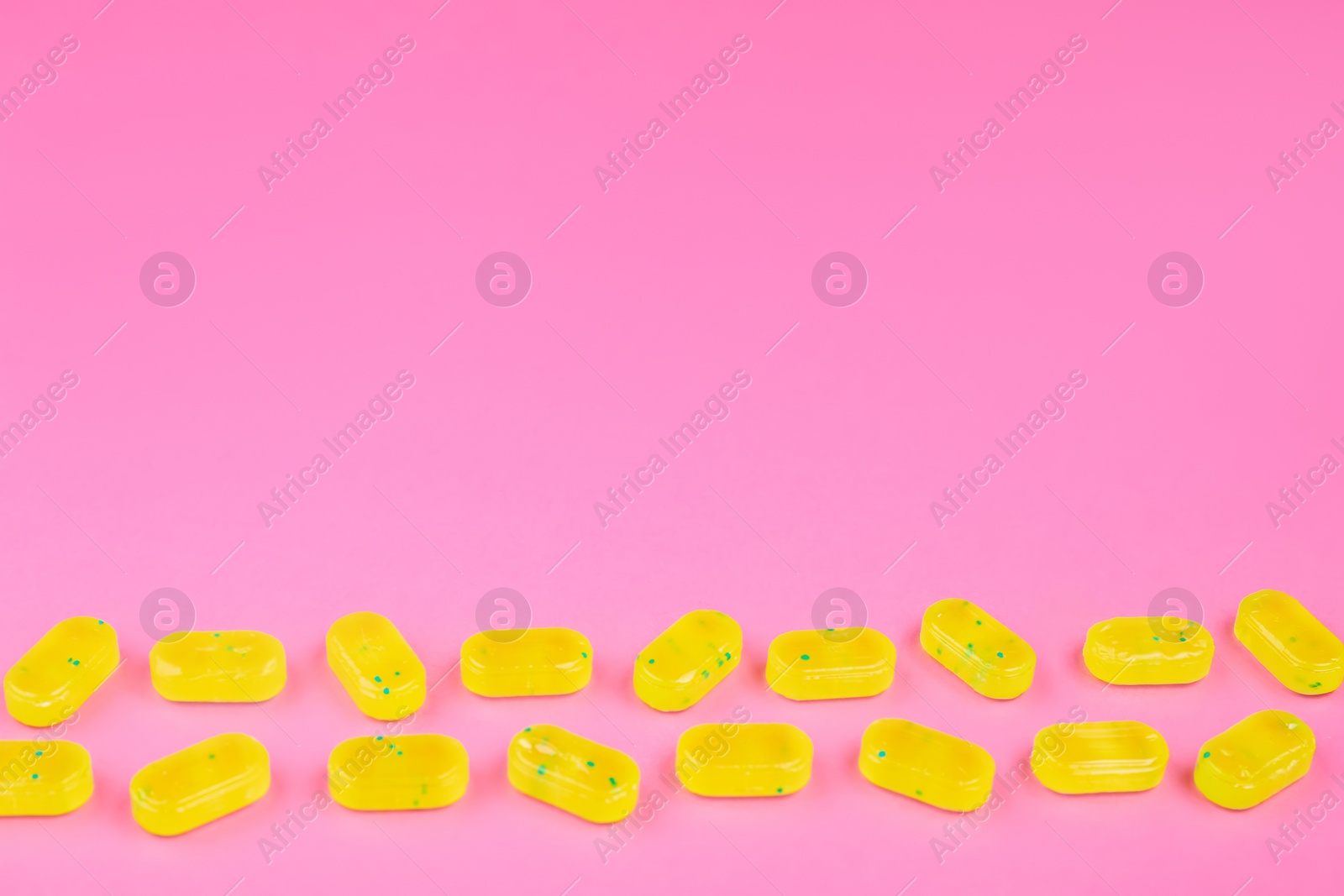 Photo of Many delicious lemon drops on pink background. Space for text