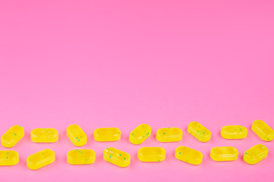 Photo of Many delicious lemon drops on pink background. Space for text