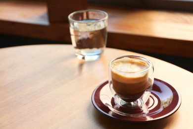 Aromatic coffee on wooden table in cafe. Space for text