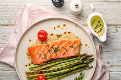 Tasty grilled salmon with tomatoes, asparagus and spices on table, flat lay