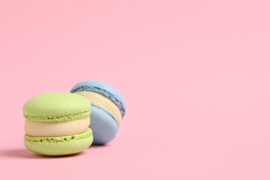 Photo of Delicious colorful macarons on pink background, space for text