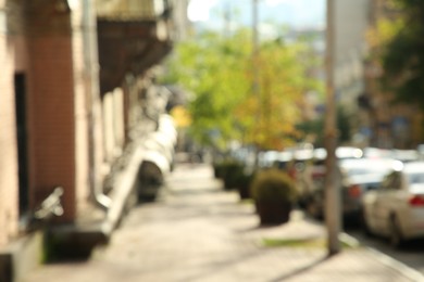 Blurred view of quiet city street with sidewalk on sunny day