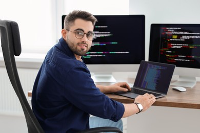 Photo of Young programmer working at desk in office