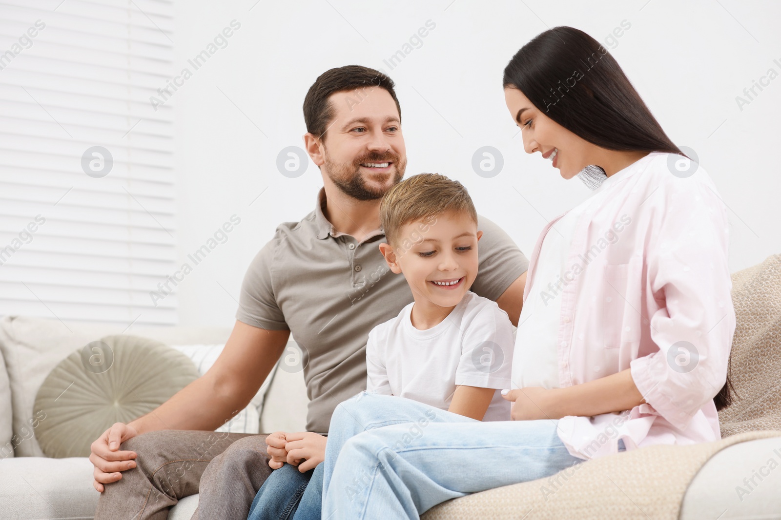 Photo of Happy pregnant woman spending time with her son and husband at home