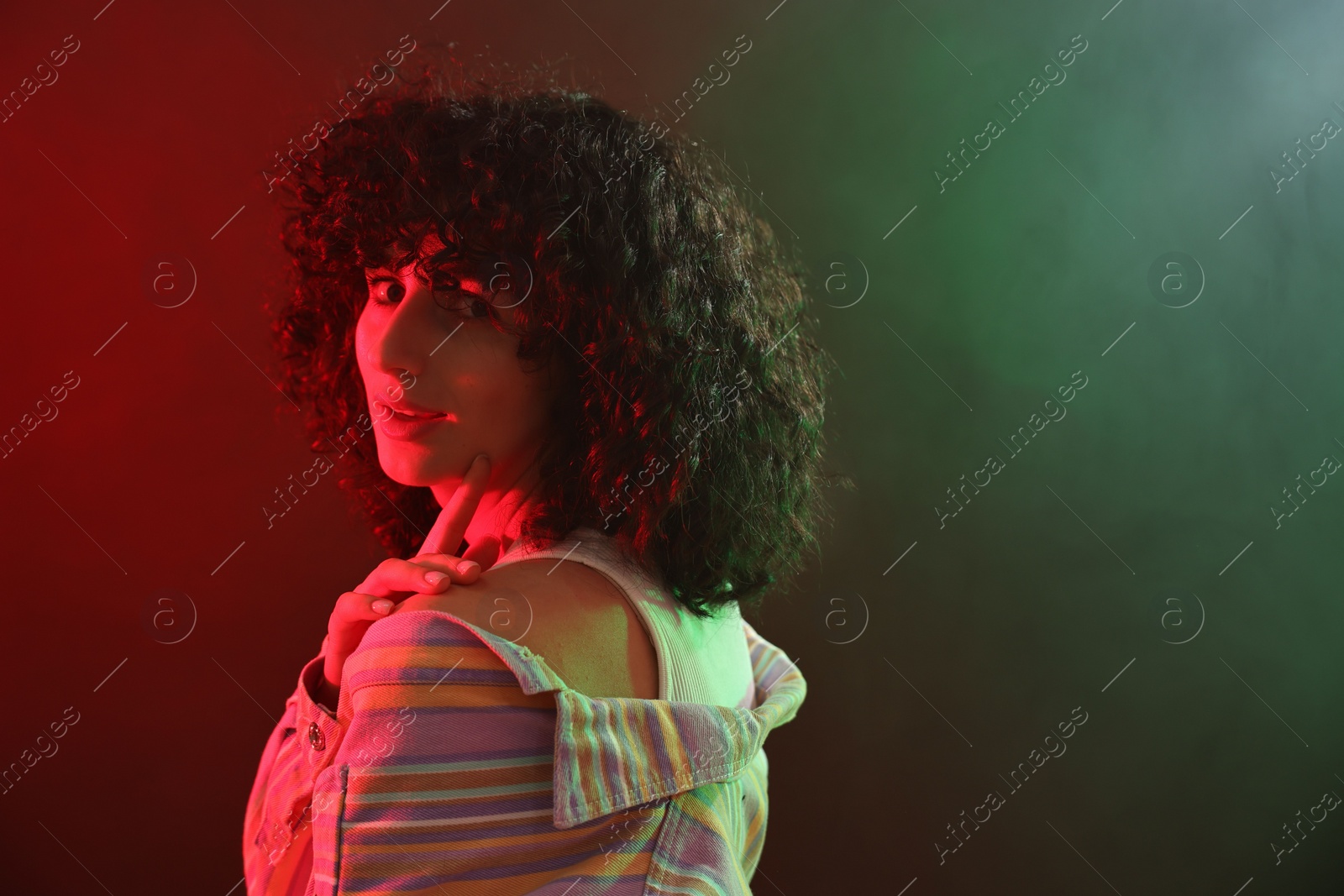 Photo of Beautiful young woman posing on color background in neon lights. Space for text