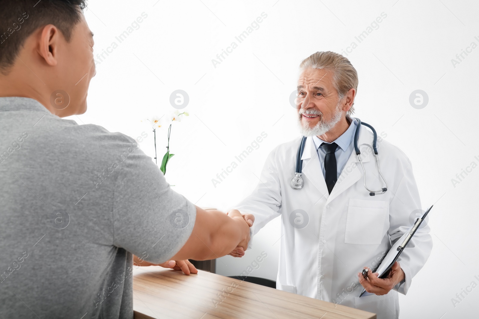 Photo of Happy doctor shaking hands with patient in hospital