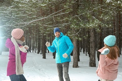 Happy family playing snowballs in winter forest