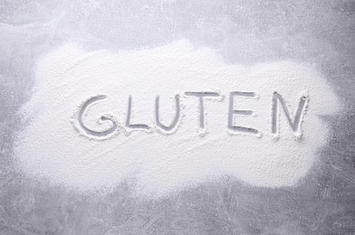Photo of Word Gluten written with flour on grey background, top view