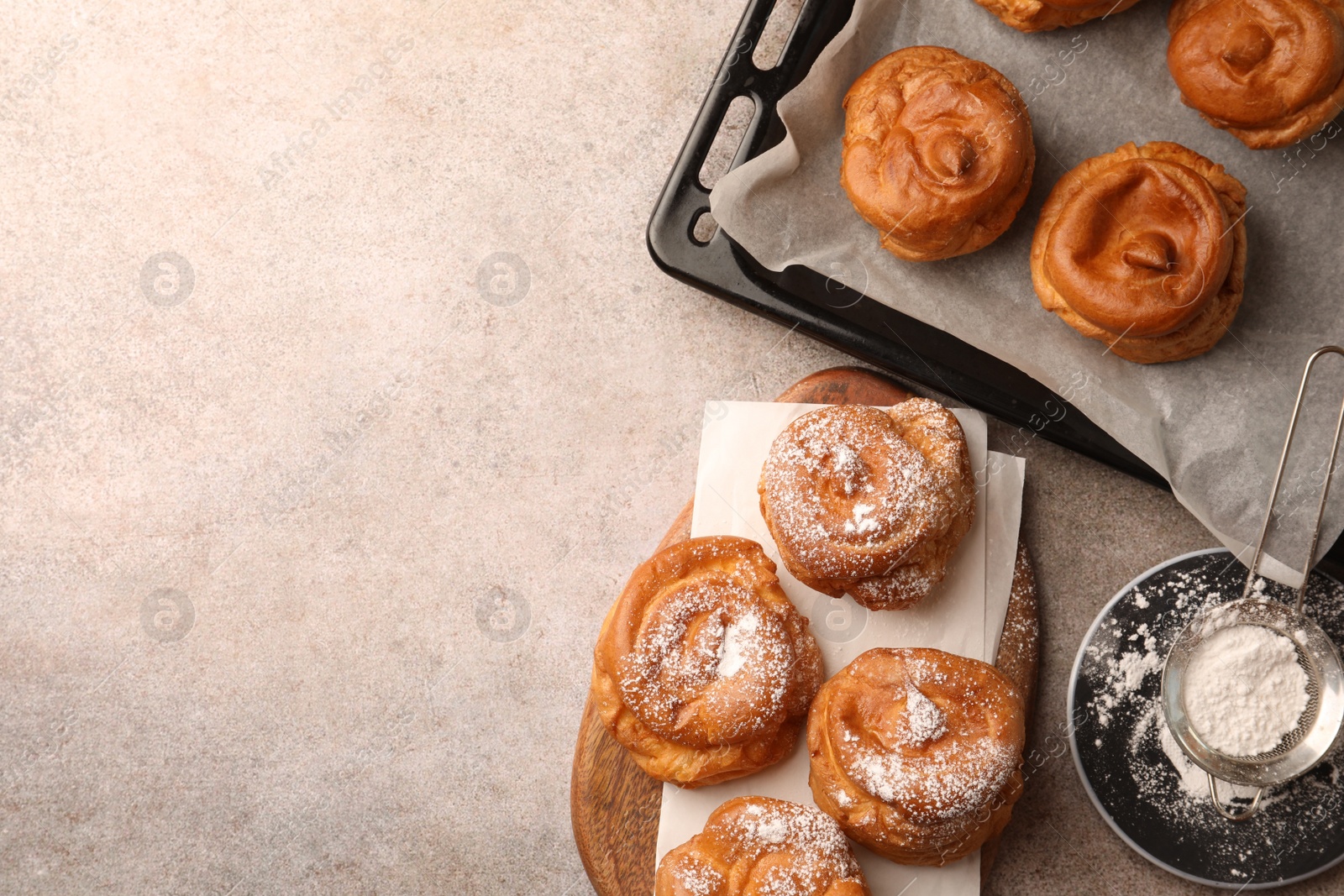 Photo of Delicious profiteroles with powdered sugar on grey table, flat lay. Space for text