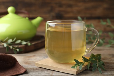 Glass cup of aromatic eucalyptus tea on wooden table, closeup