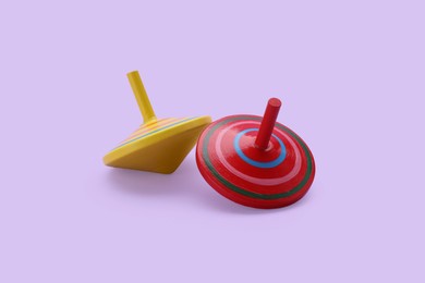 Photo of Two bright spinning tops on lilac background. Toy whirligig