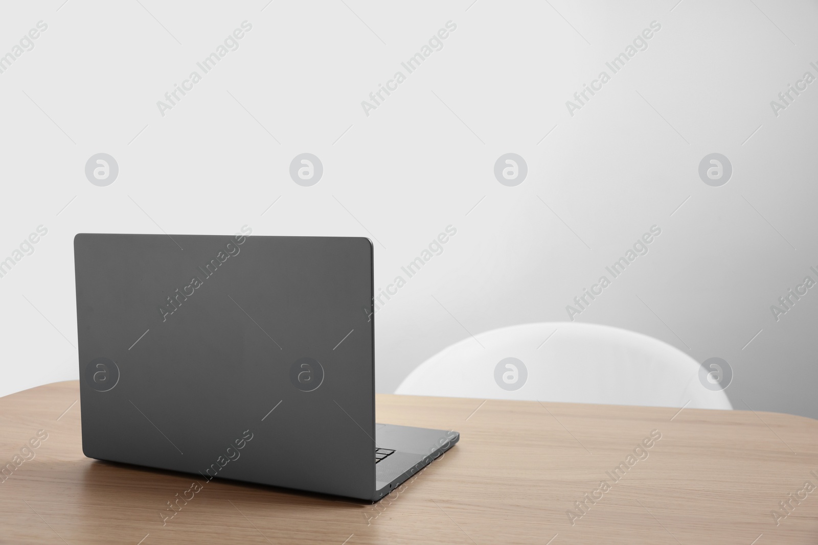 Photo of Stylish modern laptop on wooden table indoors. Space for text