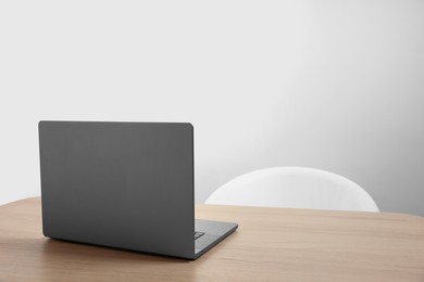 Photo of Stylish modern laptop on wooden table indoors. Space for text