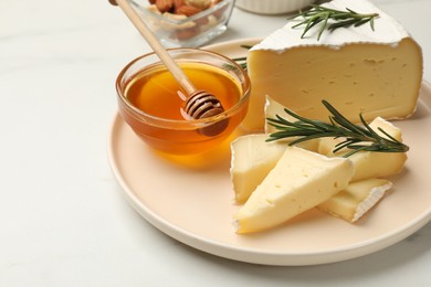 Photo of Tasty Camembert cheese with rosemary and honey on white table