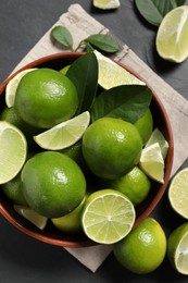 Photo of Fresh ripe limes in bowl on black table, top view