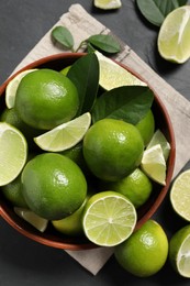 Fresh ripe limes in bowl on black table, top view