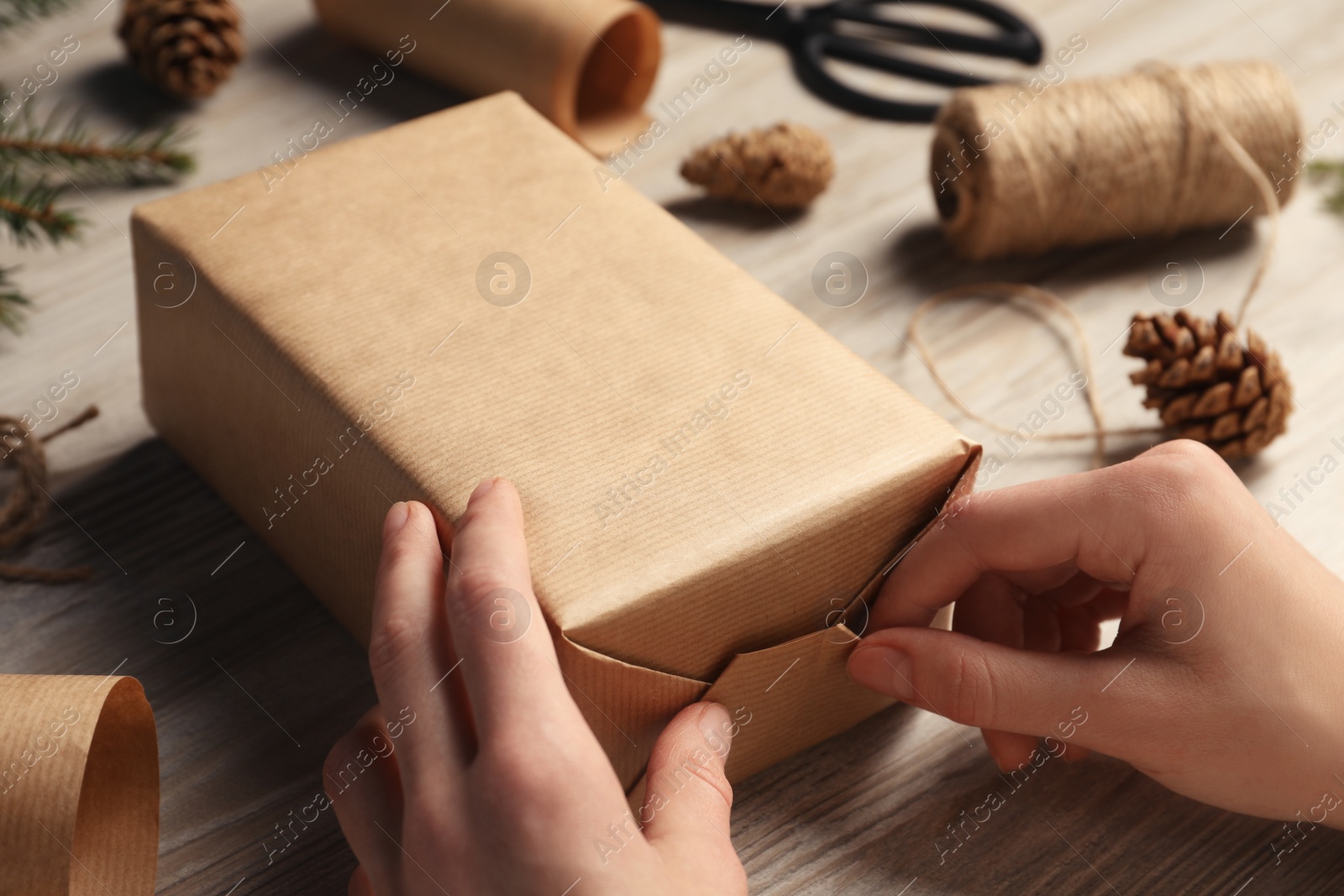 Photo of Woman decorating gift box at white wooden table, closeup. Christmas present