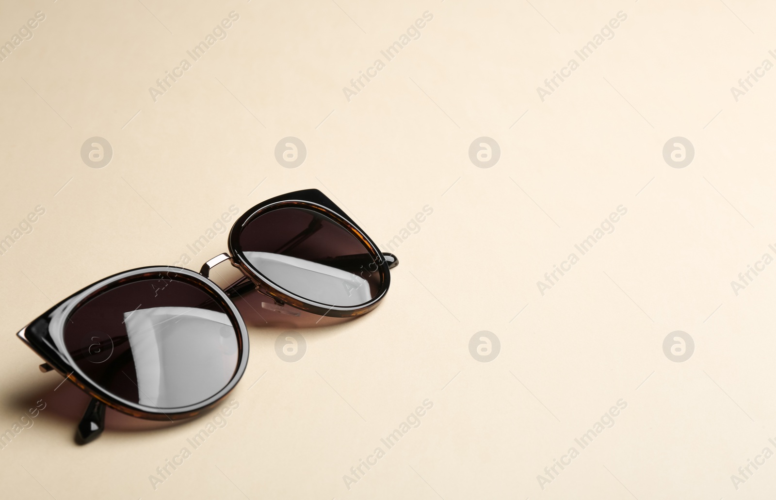 Photo of Stylish sunglasses on beige background, space for text. Fashionable accessory