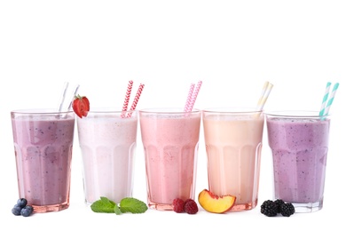 Different fresh tasty milk shakes in glasses with ingredients on white background