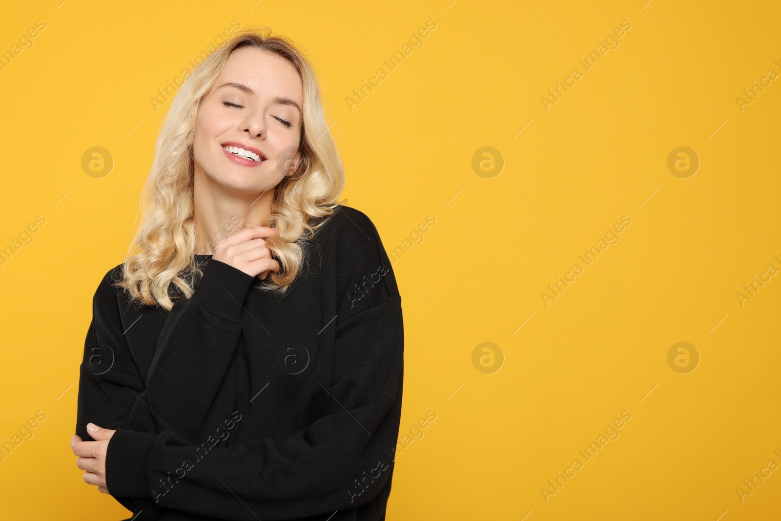 Photo of Happy woman in stylish warm sweater on orange background. Space for text