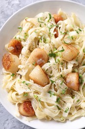 Delicious scallop pasta with spices in bowl on table, top view