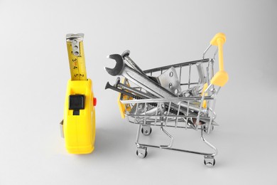 Photo of Shopping cart with different construction tools on light grey background
