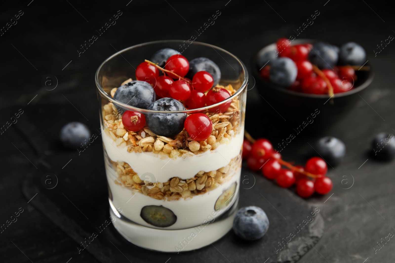 Photo of Delicious yogurt parfait with fresh berries on black table, closeup