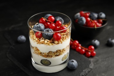 Photo of Delicious yogurt parfait with fresh berries on black table, closeup