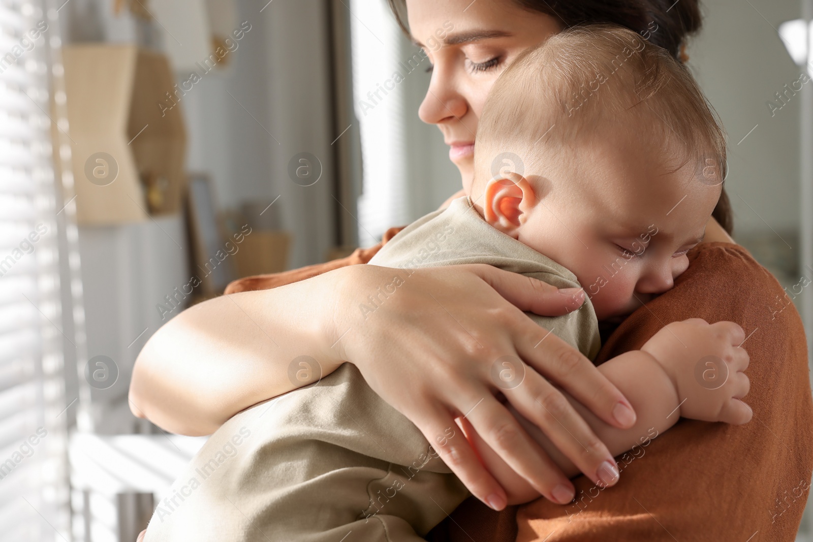 Photo of Happy young mother with her sleeping baby at home