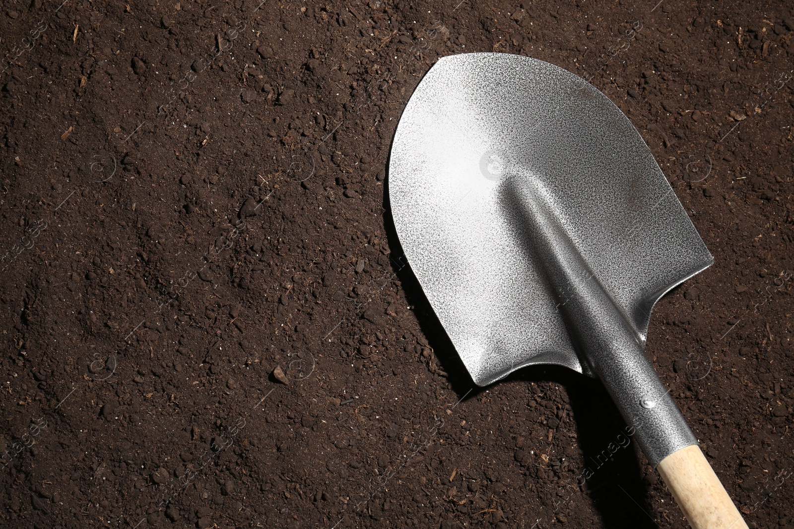 Metal shovel on fertile soil, top view and space for text. Gardening tool Photo of Metal shovel on fertile soil, top view and space for text. Gardening tool