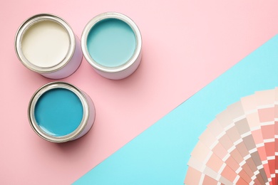 Photo of Paint cans and palette on color background, top view. Space for text