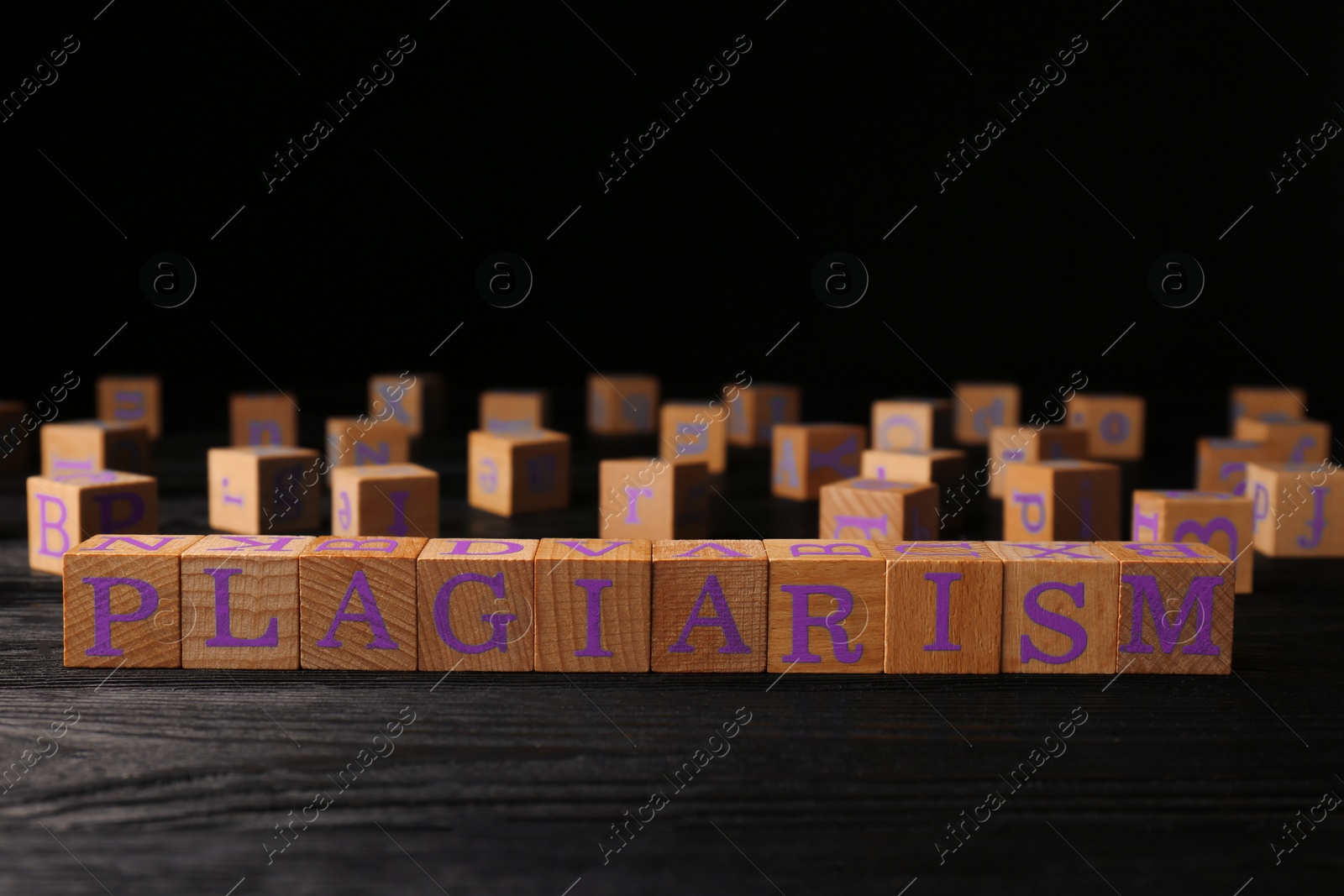 Photo of Wooden cubes with word Plagiarism on black table