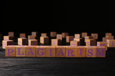 Wooden cubes with word Plagiarism on black table